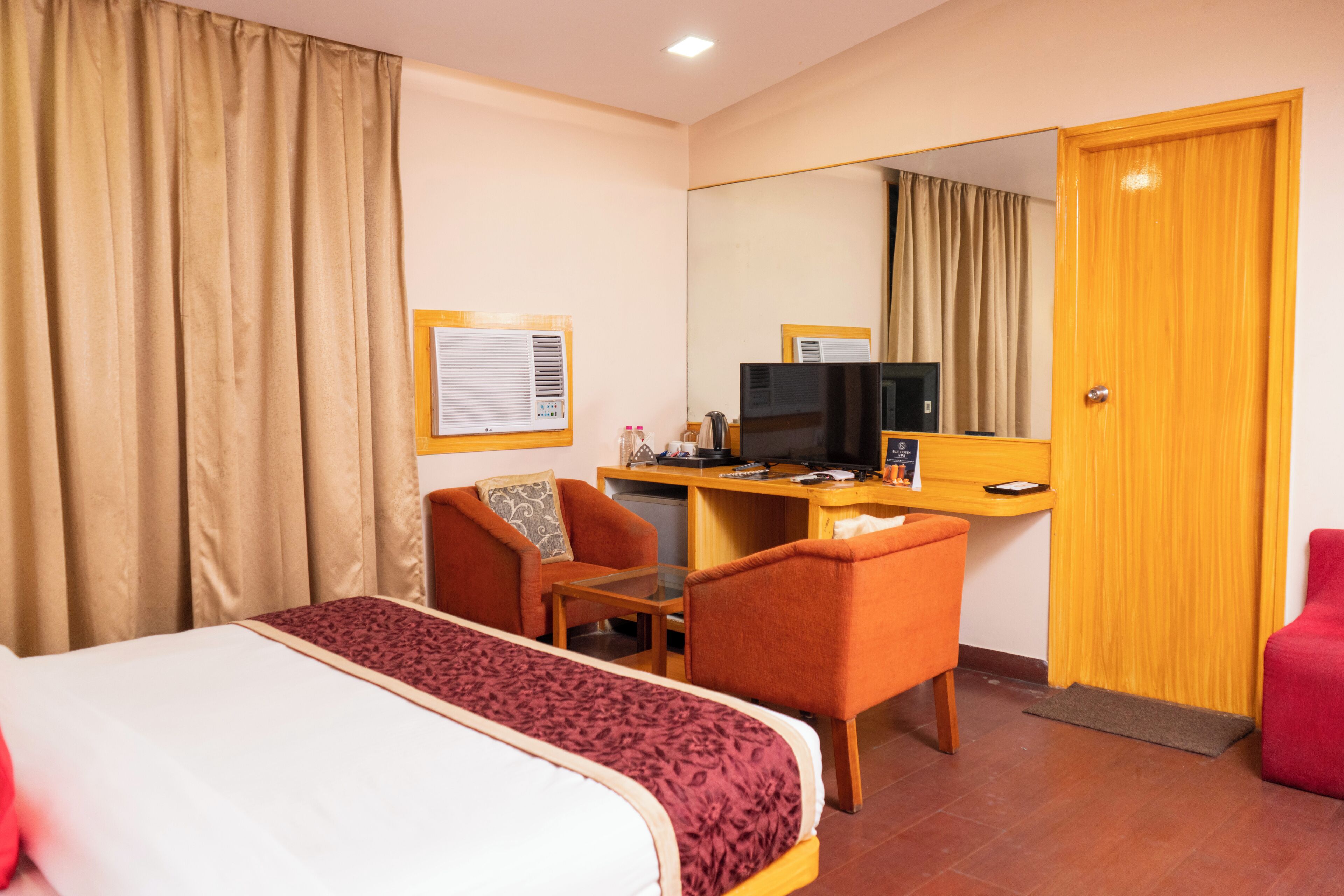 A hotel room with a bed, a desk, a chair, a television, and a wardrobe.