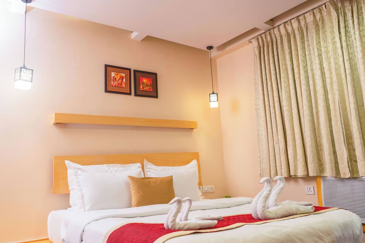 Een hotelkamer met een houten bed, witte beddengoed, een rode plaid en twee wandlampen.