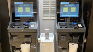 Two self-service kiosks with touchscreens, card readers, and a water dispenser in the center. - Sunrise Inn Iwaki (Iwaki)
