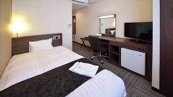 A hotel room with a bed, a desk, a television, and an air conditioning unit.