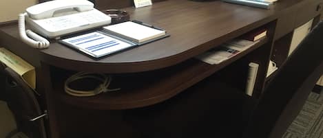 A hotel reception desk with a telephone, a notepad, a pen, a basket, and a tissue box.