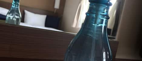 A blue bottle of Esthe Royer refreshener on a wooden surface in a hotel room.