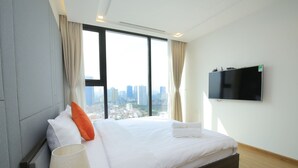 Een moderne hotelkamer met een groot bed, een aan de muur bevestigde televisie en uitzicht op de stad.