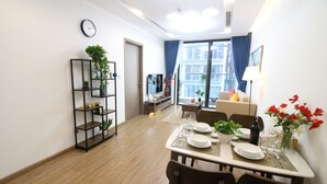 Een moderne eetruimte met een houten vloer, een eettafel gedekt voor vier personen en een boekenkast met planten.