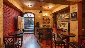 Un intérieur en bois avec un coin bar, des chaises en bois et un mur en pierre.