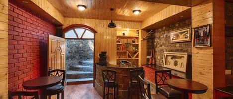 Interior de madera con una zona de bar, sillas de madera y una pared de piedra.