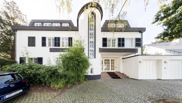 A two-story house with a white exterior, black shutters, and a driveway leading to a garage. - Hotel Villa im Park (Düsseldorf)