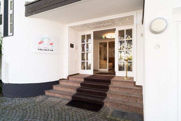 A hotel entrance with a sign reading "Villa im Park," a set of stone steps, and a glass door leading inside. - Hotel Villa im Park (Düsseldorf)