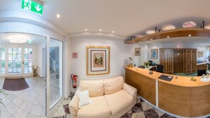 A reception area with a checkered floor, a sofa, a reception desk, and framed artwork on the walls. - Hotel Villa im Park (Düsseldorf)