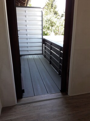 A balcony with a wooden floor and a metal railing. - Apartment Dandelion (Wolfshagen im Harz)