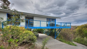 A house with a blue balcony, surrounded by greenery.