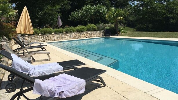 Une piscine avec des chaises longues et des parasols.