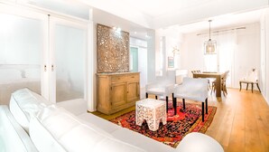 A modern living room with a white sofa, a wooden cabinet, and a patterned rug.