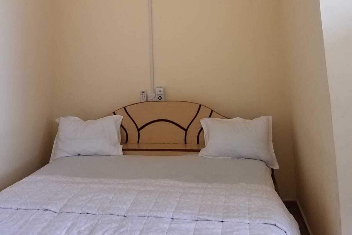 A bedroom with a bed, a ceiling fan, and an air conditioning unit.