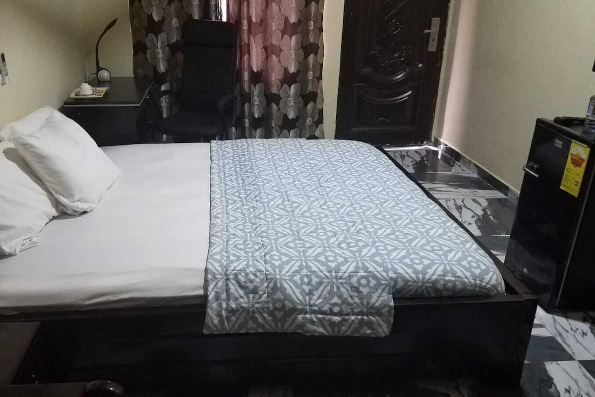 A single bed with a patterned bedspread, a bedside table with a lamp, and a curtain with a floral design.