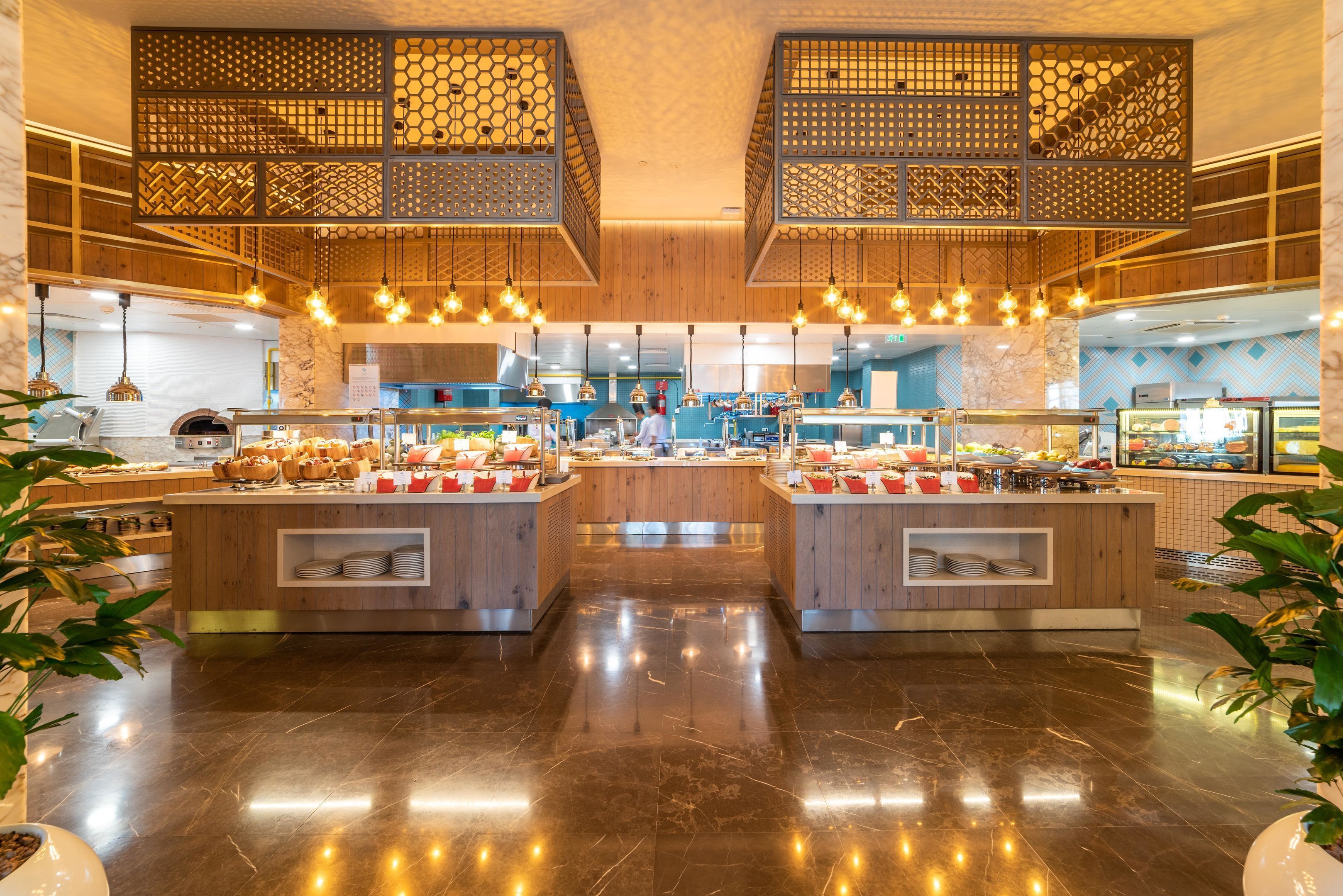 Une cuisine moderne avec des éléments en bois, un îlot central où sont présentés des aliments et des luminaires suspendus.