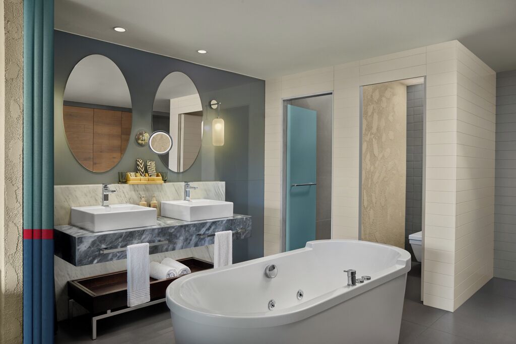 Un baño moderno con una bañera independiente, dos lavamanos y un espejo grande.