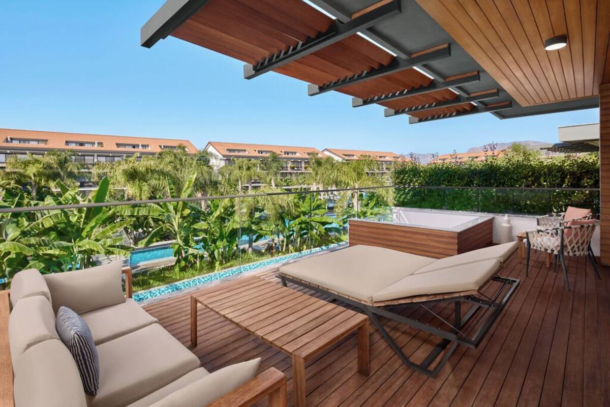 A wooden deck with a pool, lounge chairs, and a view of a residential area.