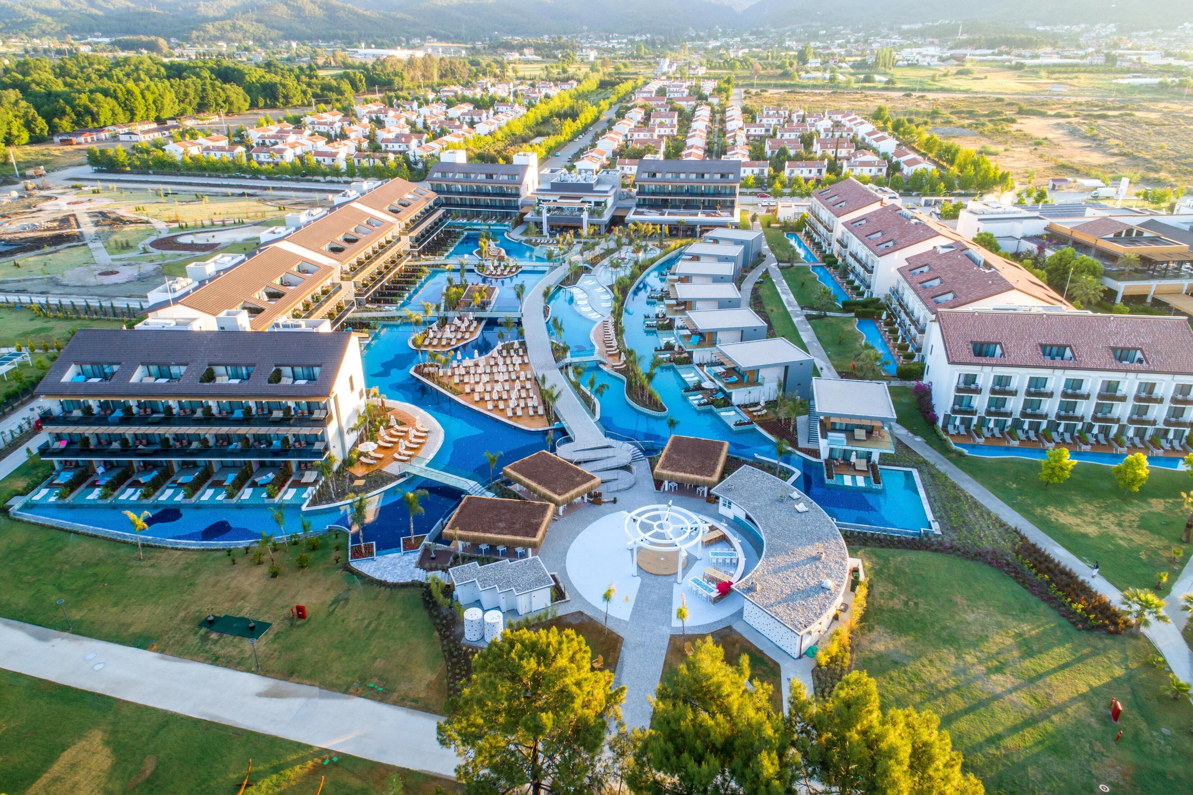 An aerial view of a resort with multiple swimming pools, a central plaza, and resort buildings.
