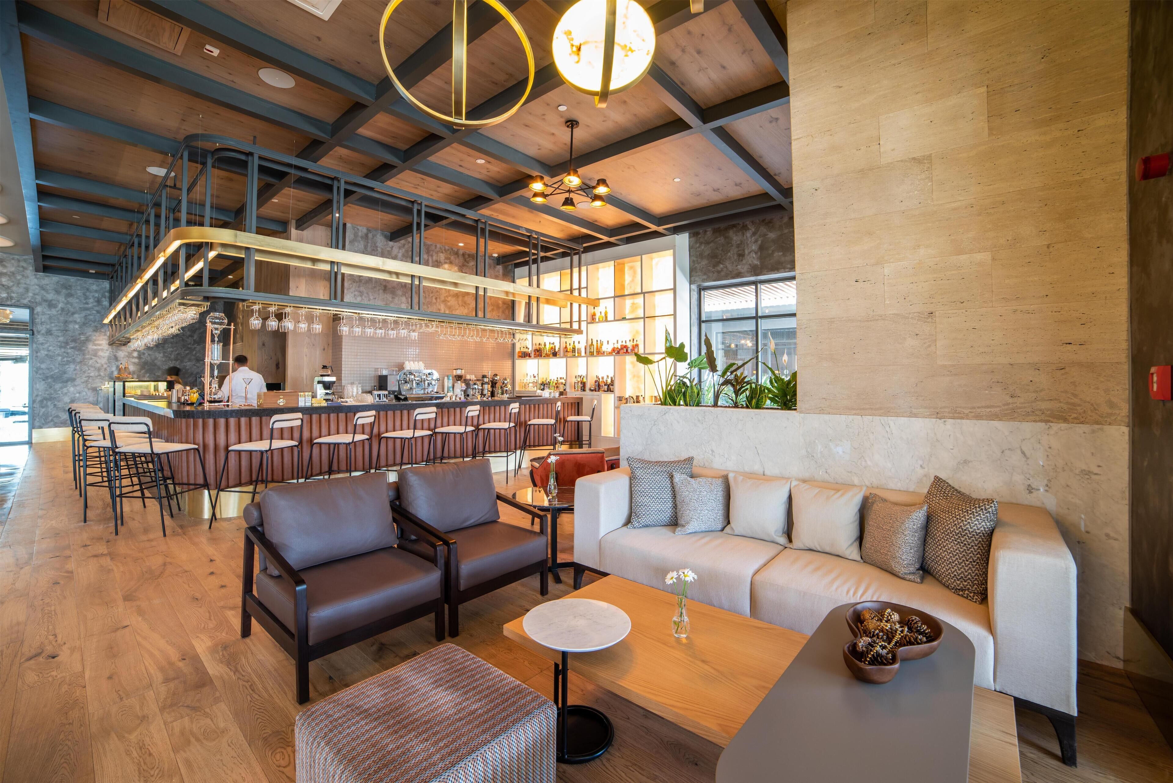 A modern bar area with a bar counter, seating, and a high ceiling with exposed beams.