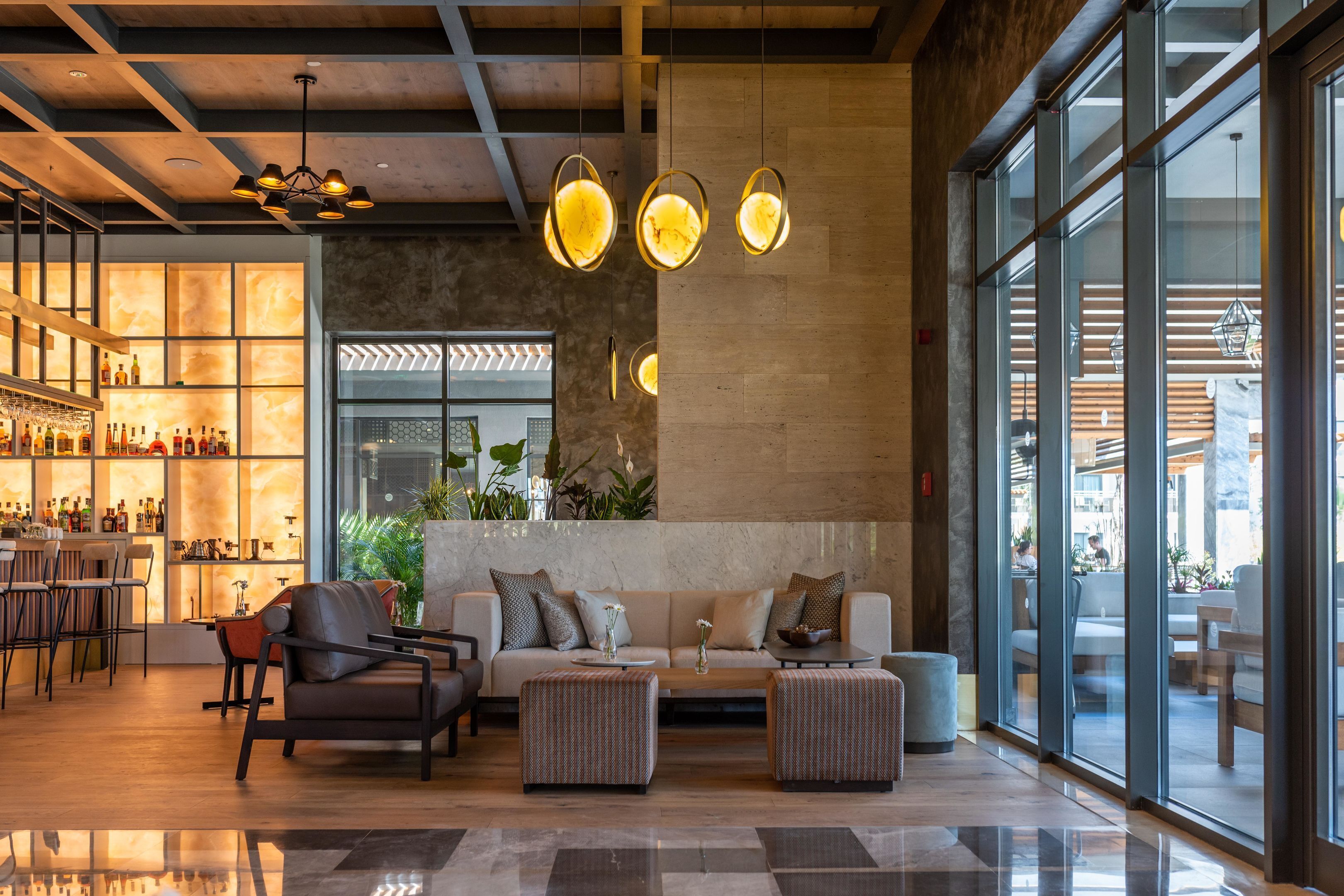 Eine moderne Lobby mit Barbereich, Sitzgelegenheiten und großen Fenstern.
