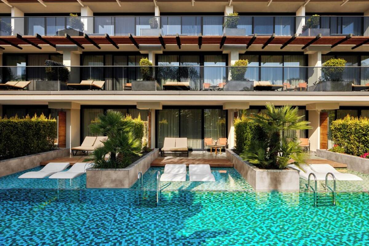 A modern hotel with a rooftop pool area, lounge chairs, and a clear view of the pool.