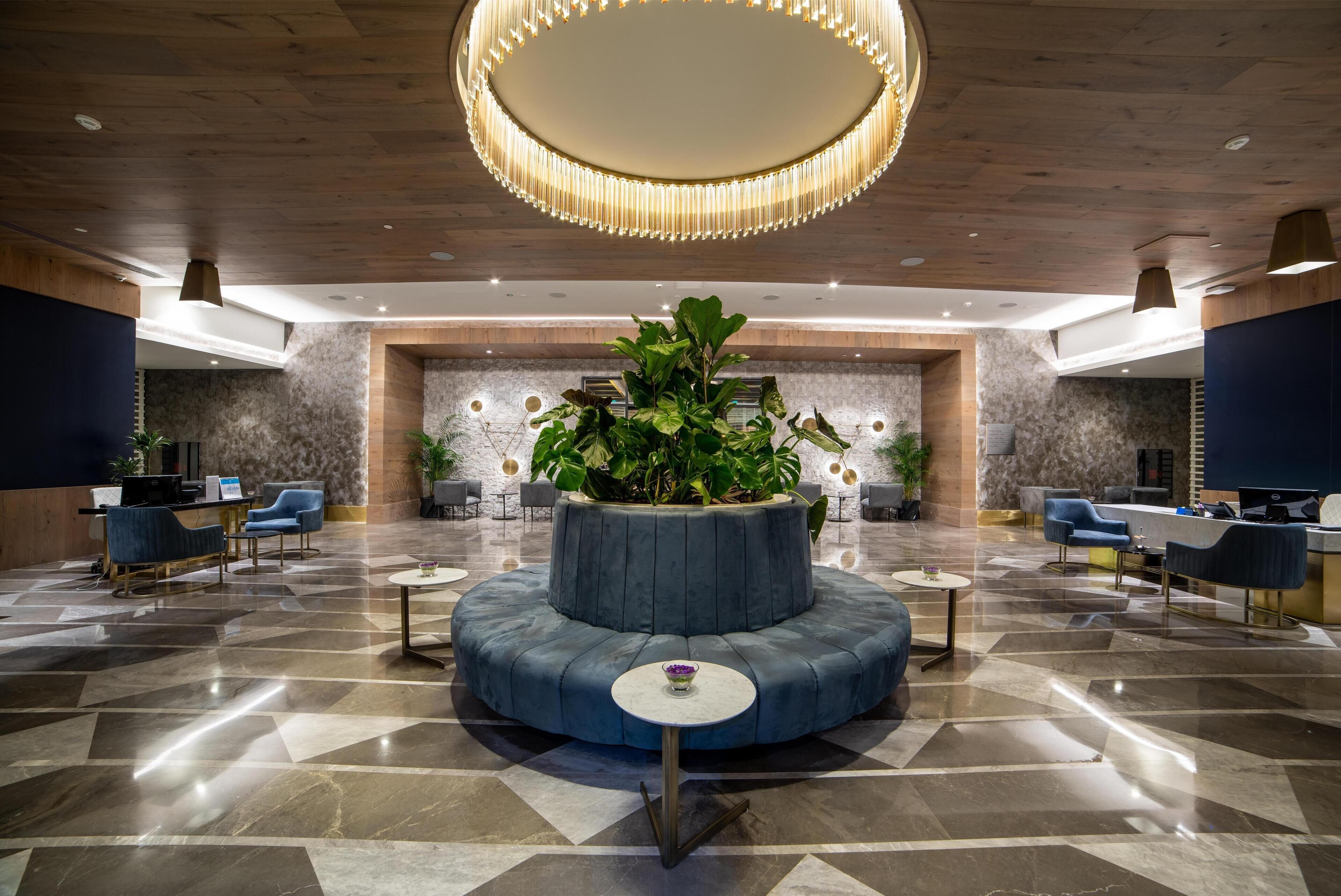 A lobby with a central seating area, a large chandelier, and a reception desk.