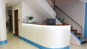 A reception desk with a laptop, potted plants, and a staircase. - Hotel Nettuno (Montecatini Terme)