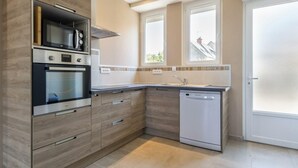 Una cocina moderna con electrodomésticos integrados, lavavajillas y un ventanal que proporciona luz natural.