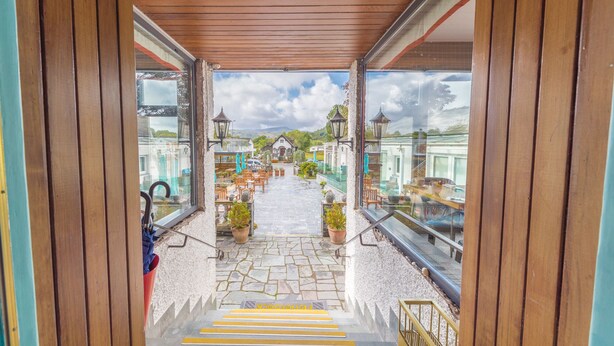 A covered outdoor area with a stone floor, potted plants, and outdoor seating. - The Fisherbeck (Ambleside)