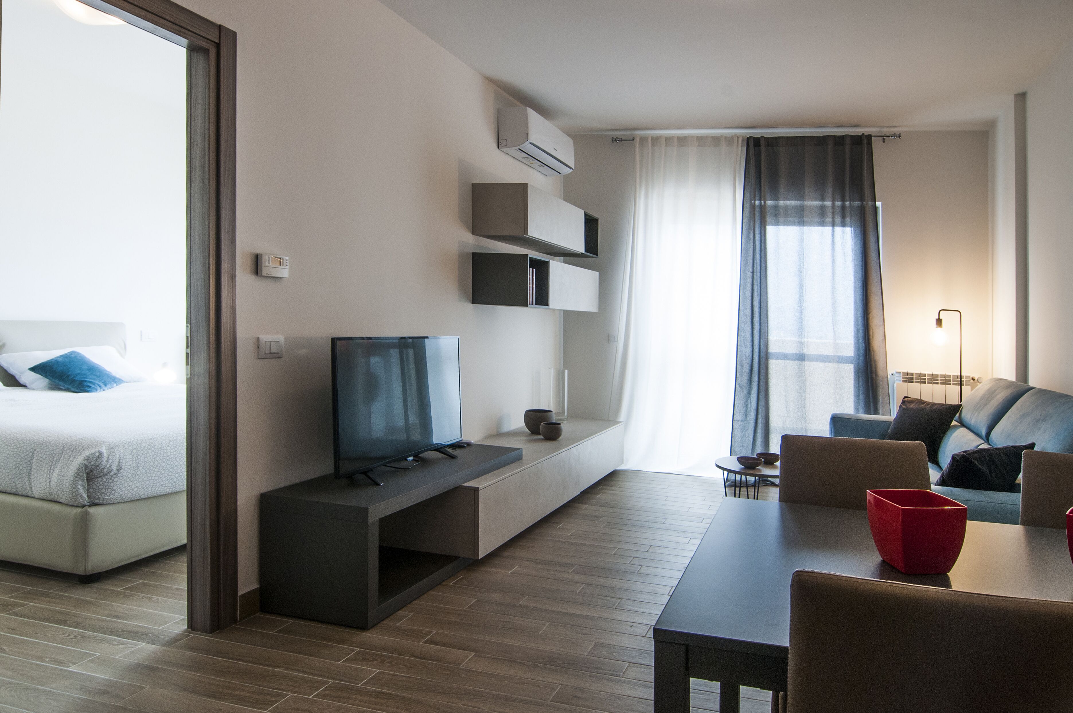 Una habitación de hotel moderna con cama, televisor, zona de estar y mesa de comedor.