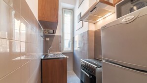 A modern kitchen with a built-in oven, a stainless steel refrigerator, and a wooden cabinet. - Cozy Flat Borgo Pio (Rome)