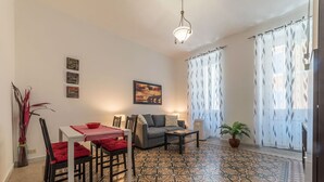 A living room with a patterned floor, a sofa, a coffee table, a dining table with chairs, and a potted plant. - Cozy Flat Borgo Pio (Rome)
