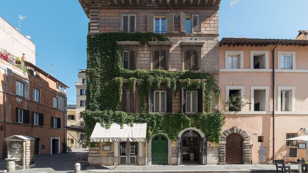 A multi-story building with a green door and a shop entrance. - Cozy Flat Borgo Pio (Rome)