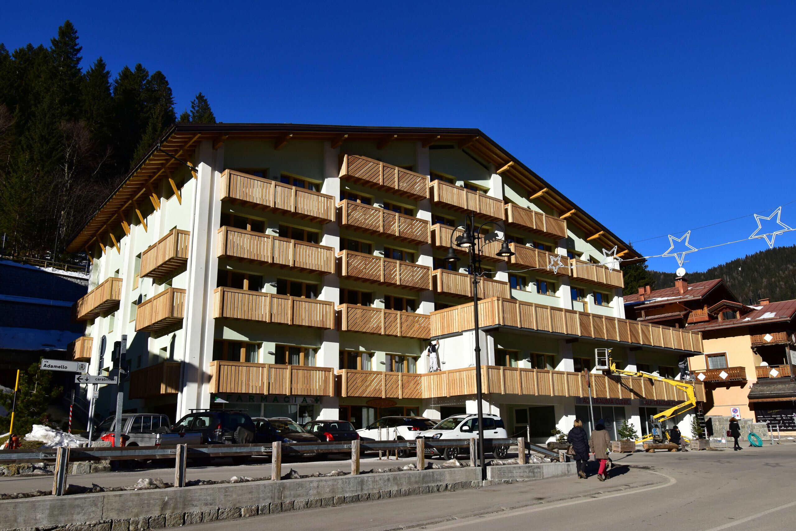 Un hôtel à plusieurs étages doté de balcons en bois, d’un télésiège et d’un parking.