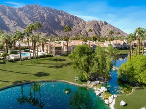 A resort with multiple villas, a swimming pool, and a mountain backdrop.