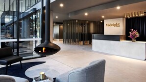 Un moderno vestíbulo de hotel con chimenea, zona de estar y mostrador de recepción.