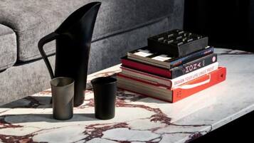 A modern living room with a grey sofa, a marble coffee table, and a stack of books.