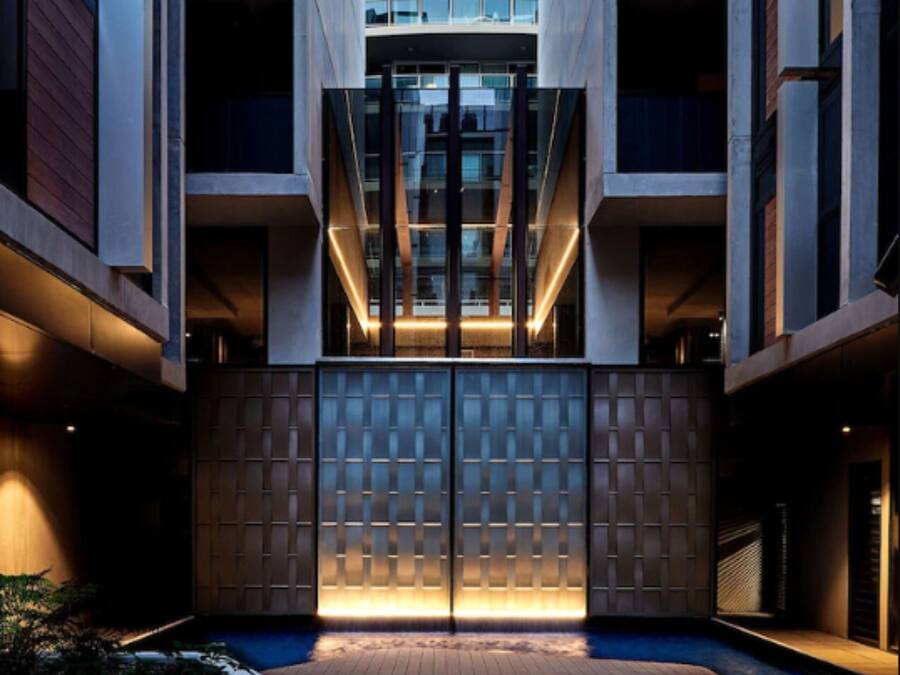 A modern building with a central courtyard, featuring a wooden deck and a glass entrance.