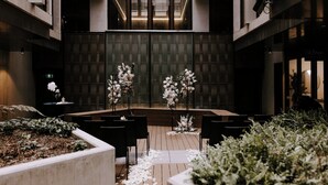 Un espacio interior moderno con un pasillo central, sillas negras y arreglos florales.
