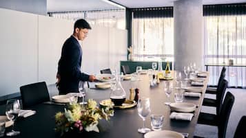 A conference room with a long table set for a meeting, featuring a modern design with a neutral color palette.