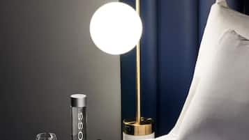 A neatly made bed with a white pillow and a round table lamp with a gold base.