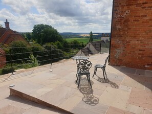 Een terras met een tafel en stoelen, een bakstenen muur en uitzicht op het landschap.