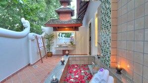 A serene spa area with a small pool, rose petals, candles, and a towel basket. - MonPanaNont Wellness Resort & Spa (Mae Taeng)