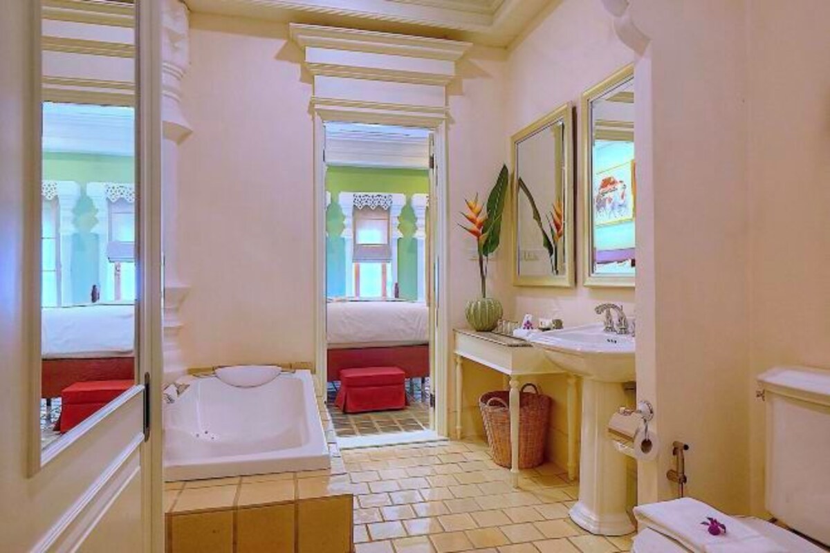 A hotel bathroom with a bathtub, a sink, a toilet, and a mirror.