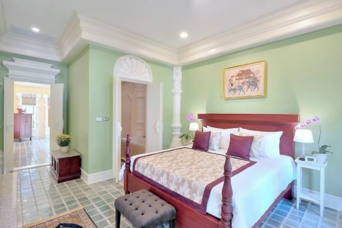 A bedroom with a four-poster bed, a nightstand, a lamp, and a painting on the wall.