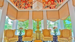 A room with four yellow patterned armchairs, a central golden table, and a ceiling mural. - MonPanaNont Wellness Resort & Spa (Mae Taeng)