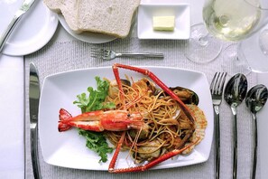 A seafood dish with a large lobster on a plate, accompanied by bread and a small dish of butter.