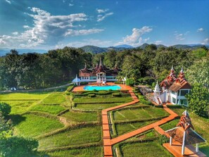A terraced rice field with a swimming pool and traditional architecture. - MonPanaNont Wellness Resort & Spa (Mae Taeng)