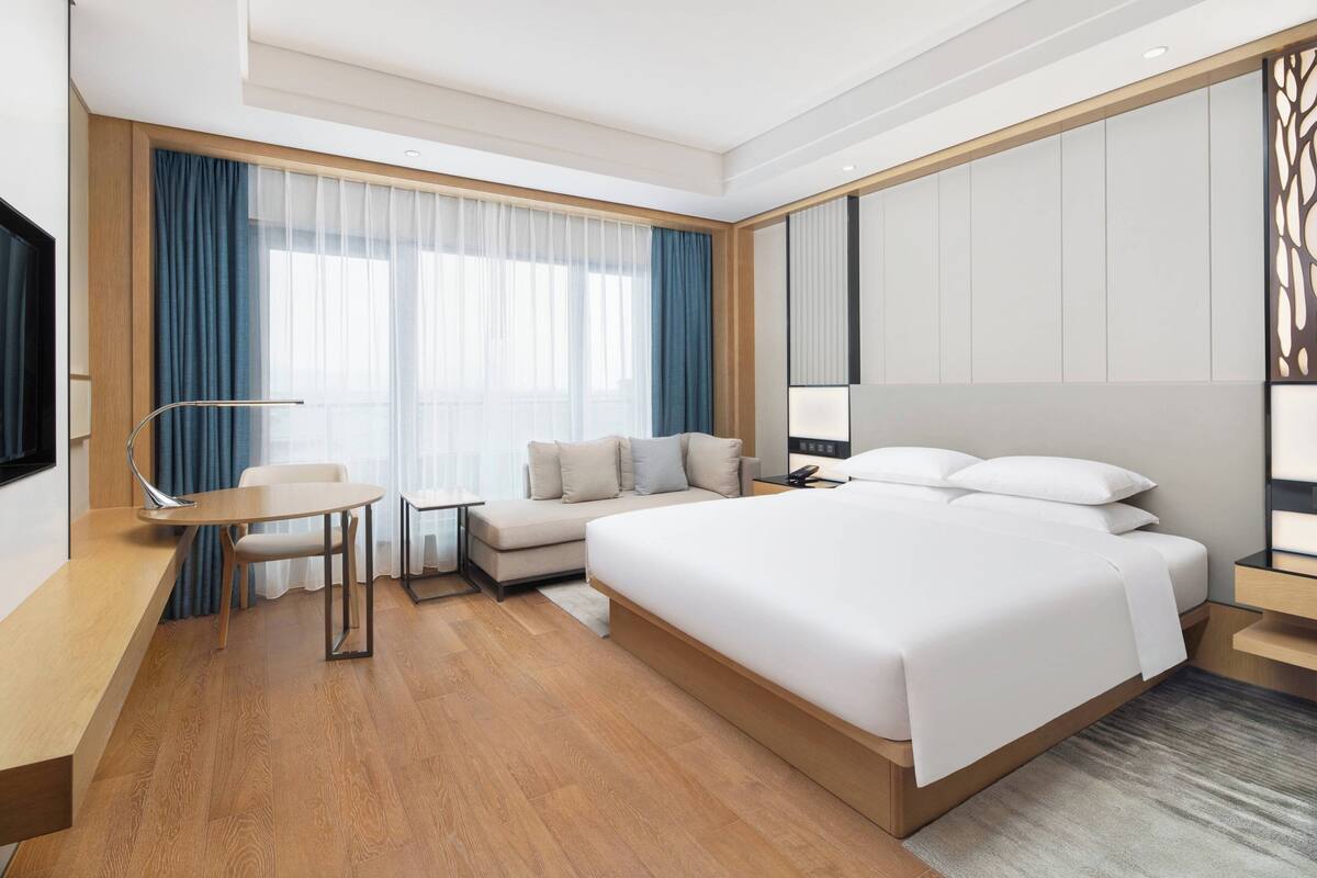 Una habitación de hotel moderna con una cama grande, un escritorio, una silla y un televisor.